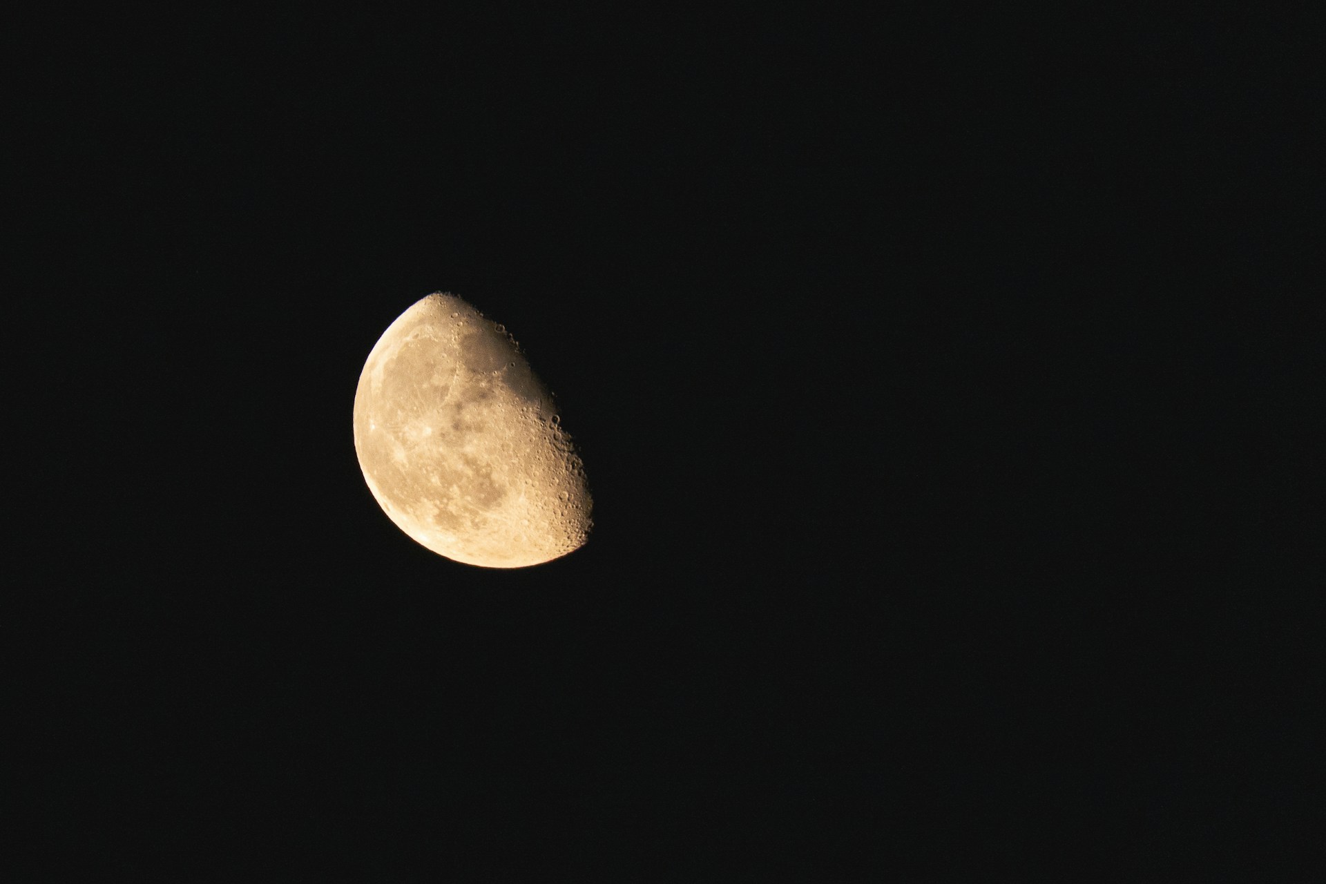 a half moon is seen in the dark sky