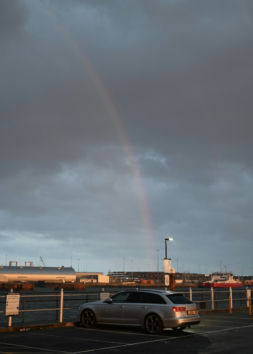 a car parked in a parking lot under a rainbow