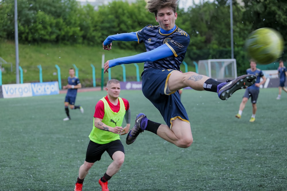 a man kicking a soccer ball on top of a field