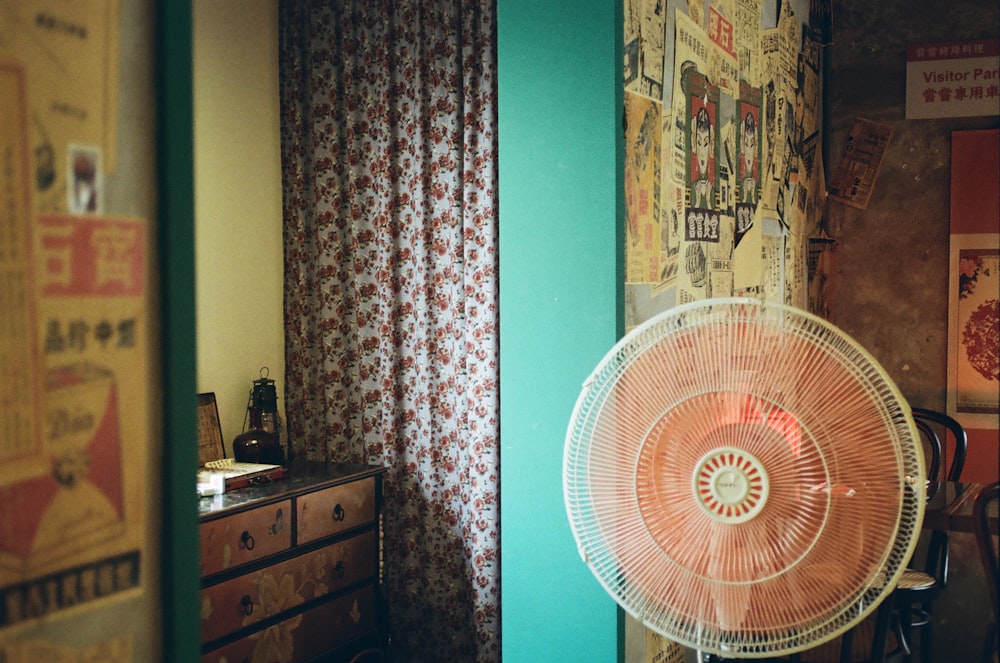 a fan sitting on top of a table next to a dresser