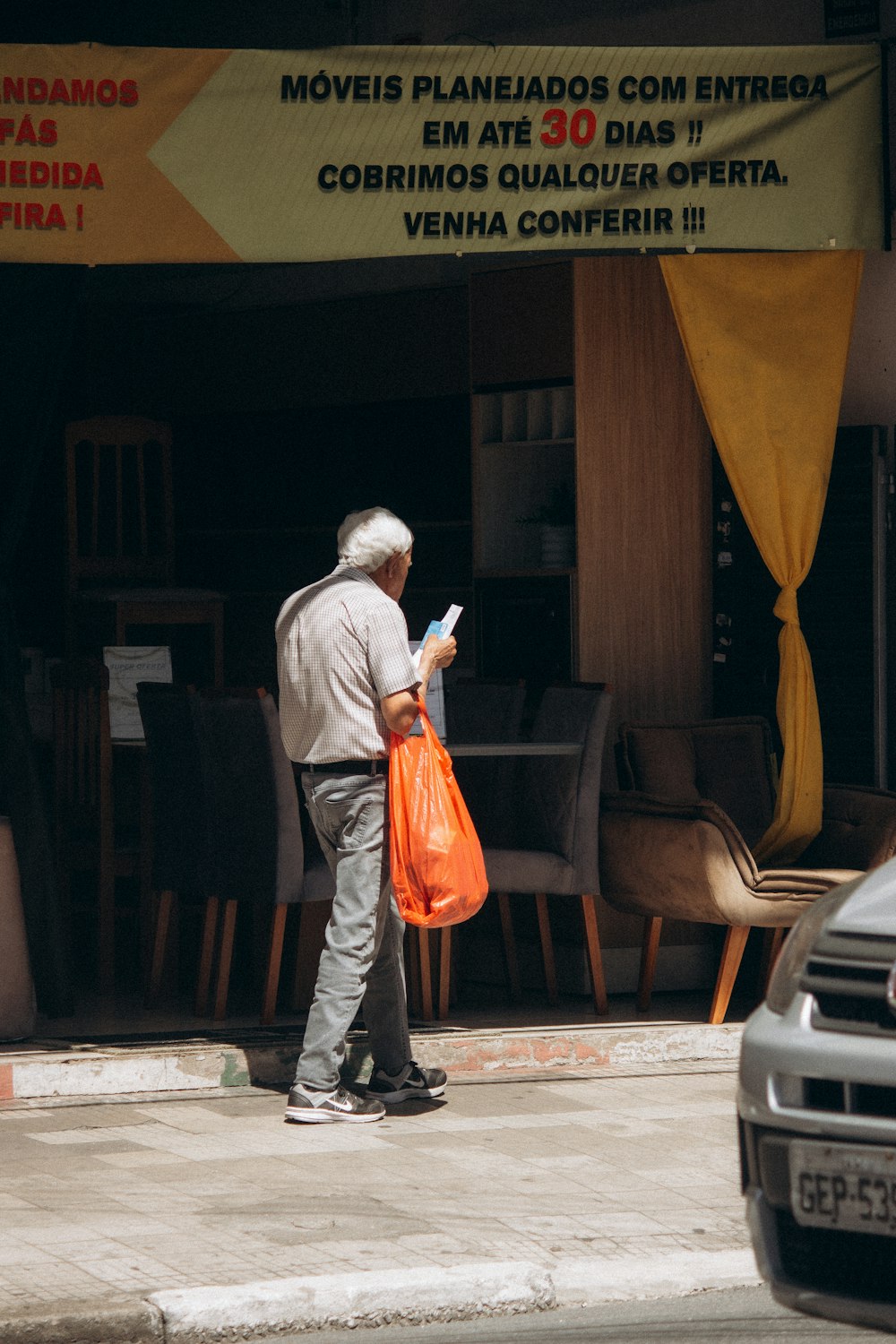 a man standing on the side of a street holding a bag