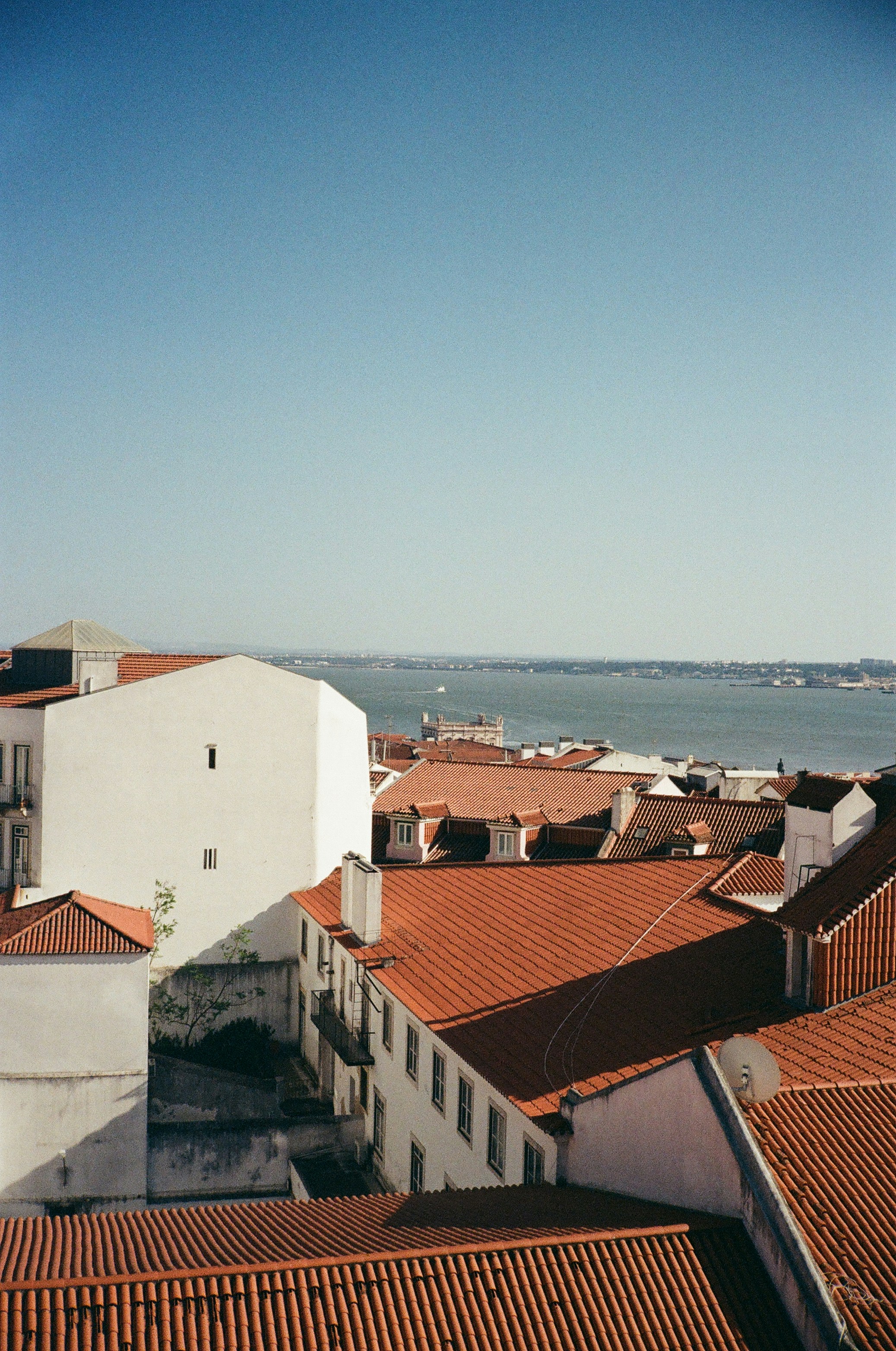 a view of a city with red roofs and a body of water in the distance