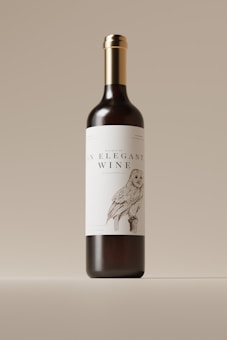 A wine bottle with a sleek and elegant design is centered against a neutral background. The label features an illustration of an owl, adding a touch of artistic charm, and prominently displays the text 'An Elegant Wine.' The bottle has a dark body with a shiny metallic gold cap.