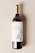 A wine bottle with a gold foil cap and a cream-colored label featuring an illustration of an owl. The label text reads 'An Elegant Wine.' The background is a neutral, soft beige color.