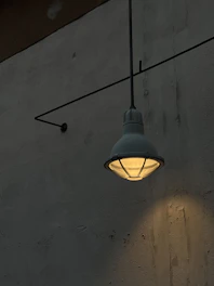An industrial metal wall sconce casting a subtle light on a textured wall.