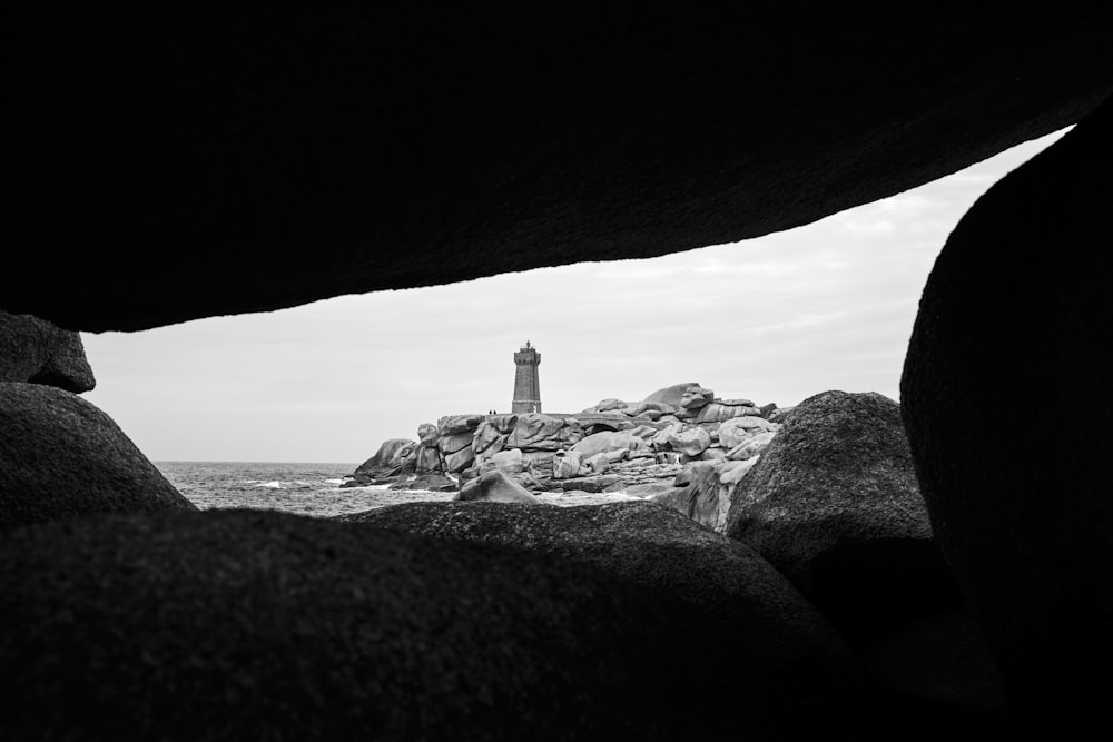 Ein Schwarz-Weiß-Foto von einem Leuchtturm und Felsen