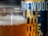 A glass filled with amber-colored beer is in focus, showcasing a layer of frothy foam at the top. In the background, a blurry can with the visible text 'BREWDOG' and 'ALE TO THE KING' adds a sense of context to the beverage.