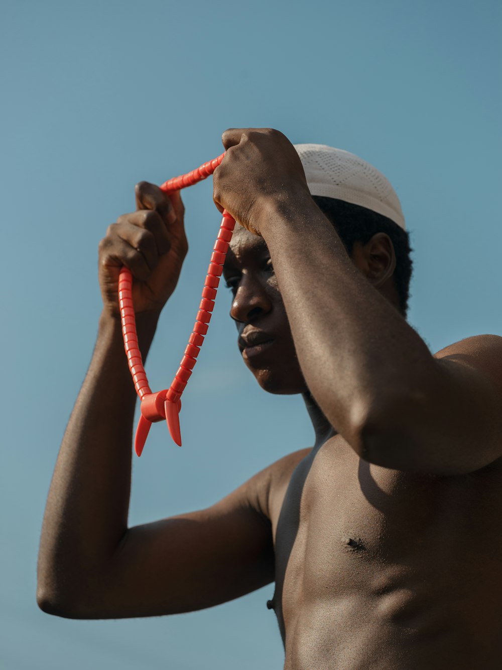 a shirtless man holding carrots up to his face