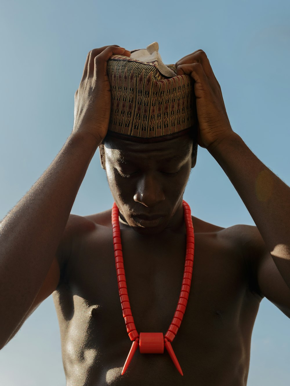 a man wearing a red beaded necklace and a hat