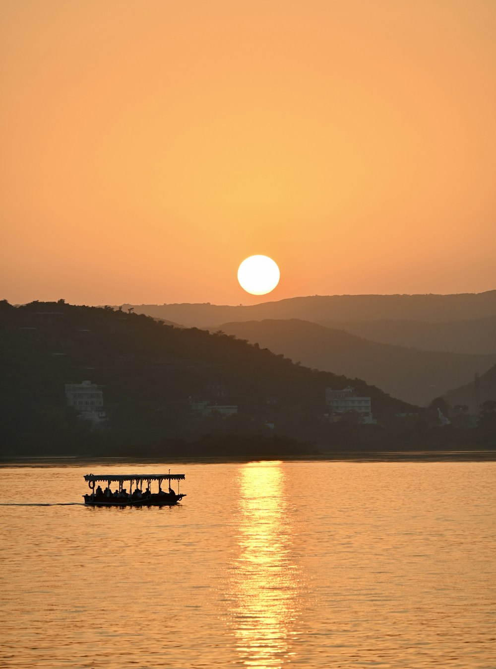 the sun is setting over the water with a boat in the foreground