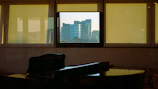 Simon playing piano by a window with Newport's scenic view in the background.