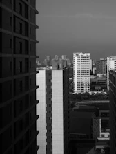 A professional black and white photo of two businessmen reviewing a residential property plan with a Michigan city skyline faintly visible in the background.