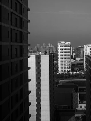 A professional black and white photo of two businessmen reviewing a residential property plan with a Michigan city skyline faintly visible in the background.