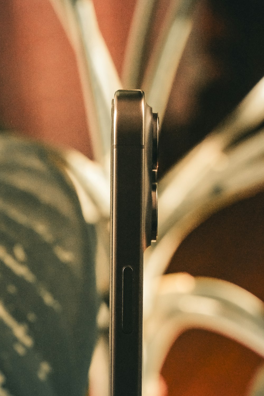 a close up of a cell phone with a plant in the background