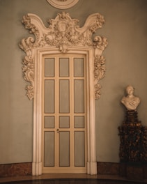 Close-up of an intricately carved 18th-century plaster door pediment in a warm, elegant interior.