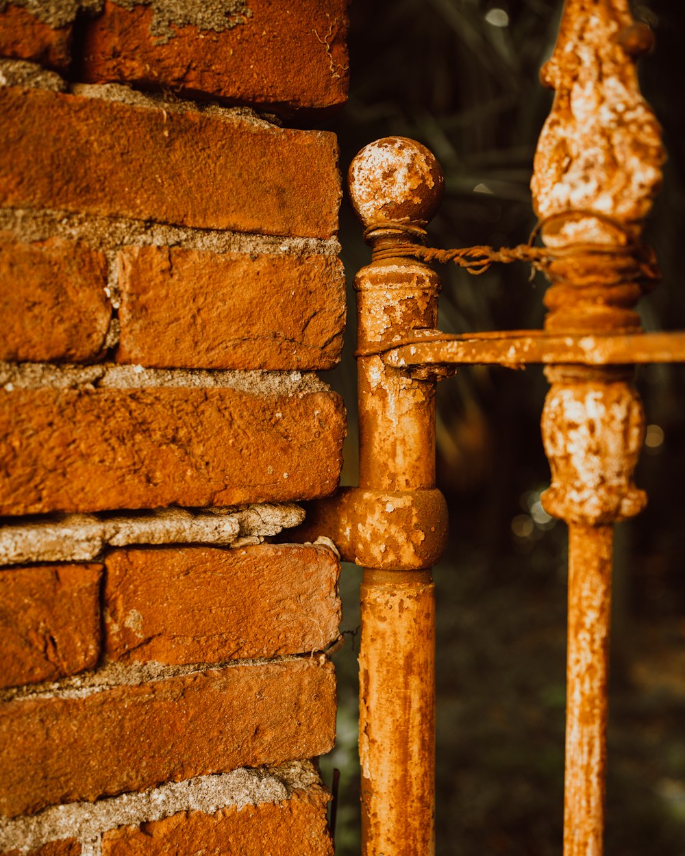 a rusted iron fence next to a brick wall