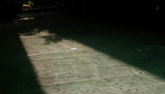 A professional inspector examining concrete with documents in hand under bright site lighting.