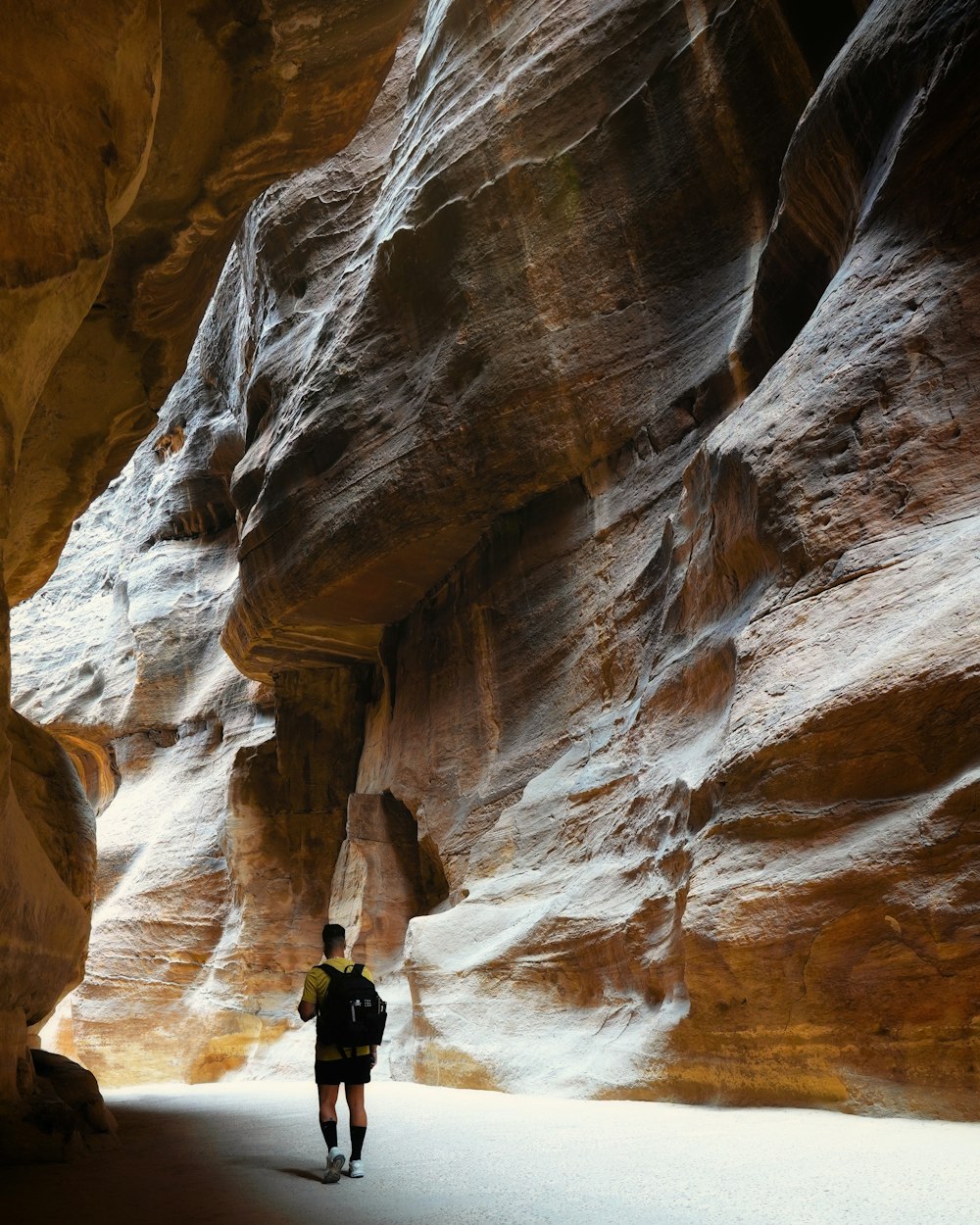 a man walking through a narrow slot in a canyon