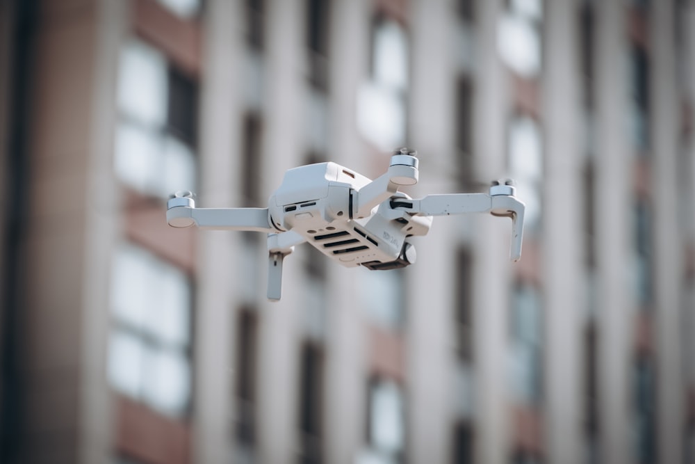 a small white object flying in front of a tall building