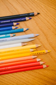Close-up of colorful markers and pencils arranged neatly on a wooden desk.