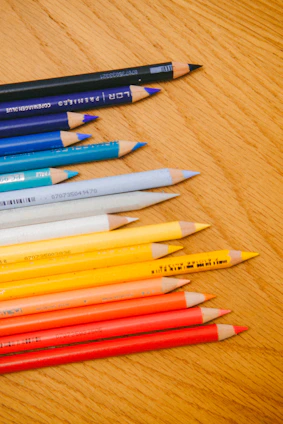 Close-up of colorful pens and pencils neatly arranged on a wooden desk