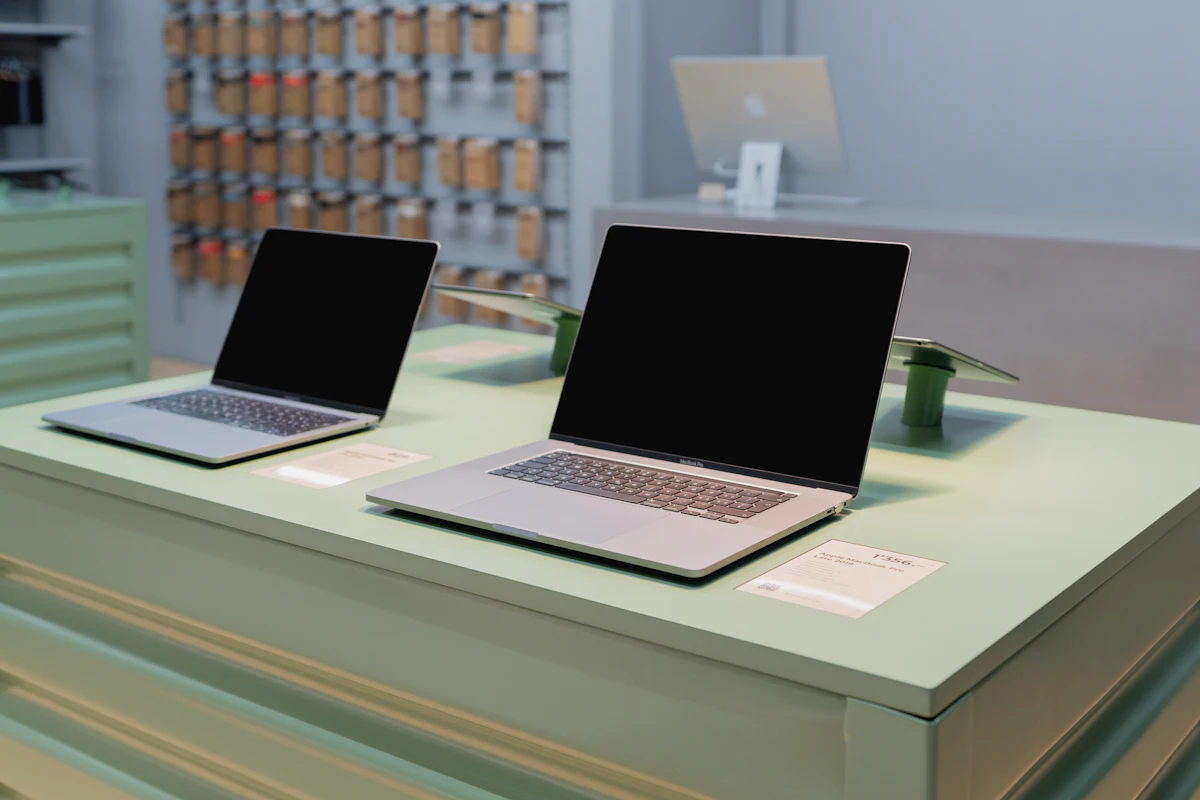 Deux ordinateurs portables exposés sur une table de magasin avec leurs étiquettes de prix