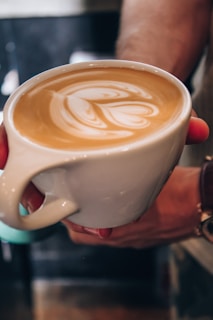Close-up of latte art shaped like a heart in a handmade ceramic mug