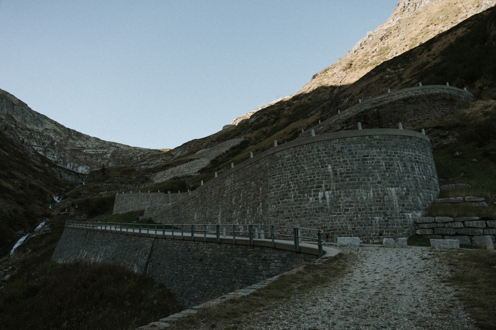 a large stone wall next to a mountain