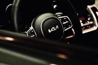 Close-up of a sleek steering wheel illuminated by ambient orange light in a modern car interior.