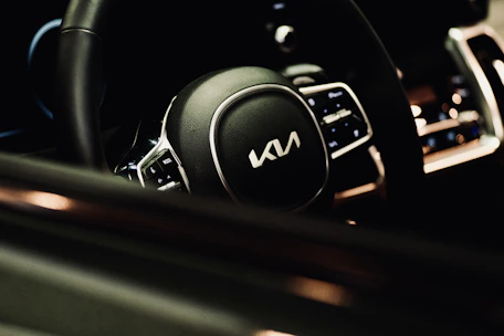 Close-up of a shiny steering wheel inside a luxury rental car with ambient lighting.