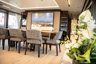 A modern dining room with a wooden table surrounded by elegant chairs and a centerpiece.