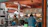 A cheerful customer enjoying a colorful plate of food at a bustling food court table.