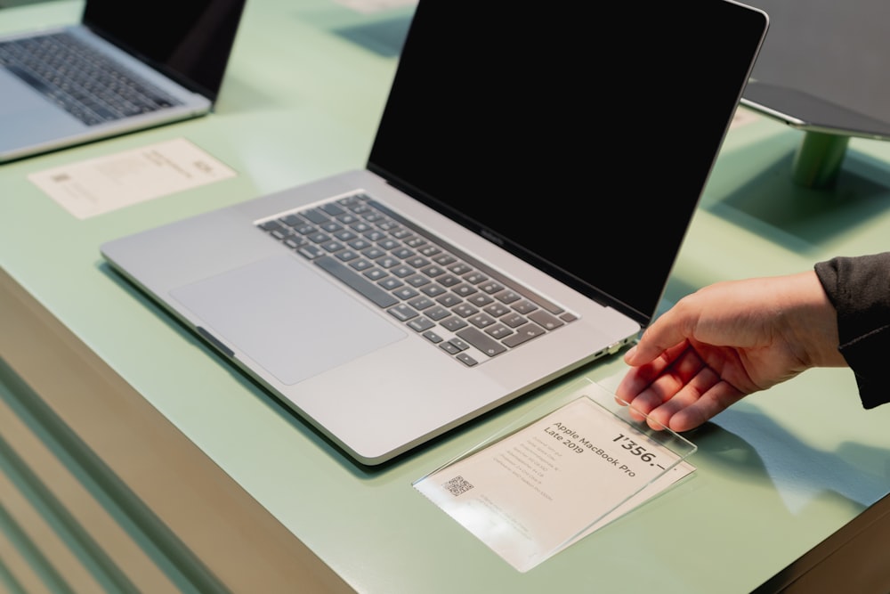 a person's hand on top of a laptop computer