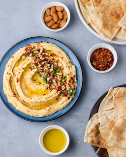 a plate of hummus, pita bread, and a bowl of olive oil