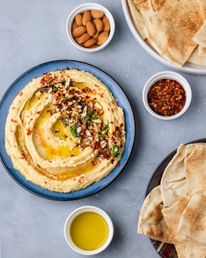 a plate of hummus, pita bread, and a bowl of olive oil