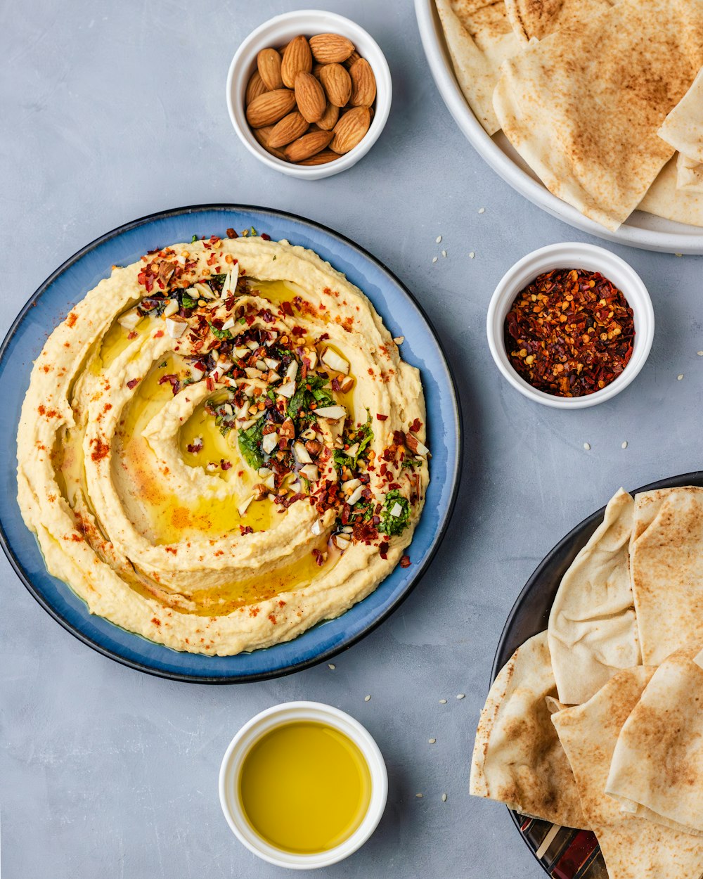 a plate of hummus, pita bread, and a bowl of olive oil