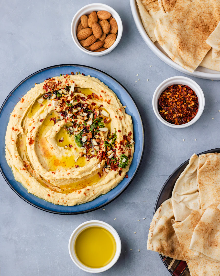 Hummus with olive oil, herbs, almonds, and pita on the side