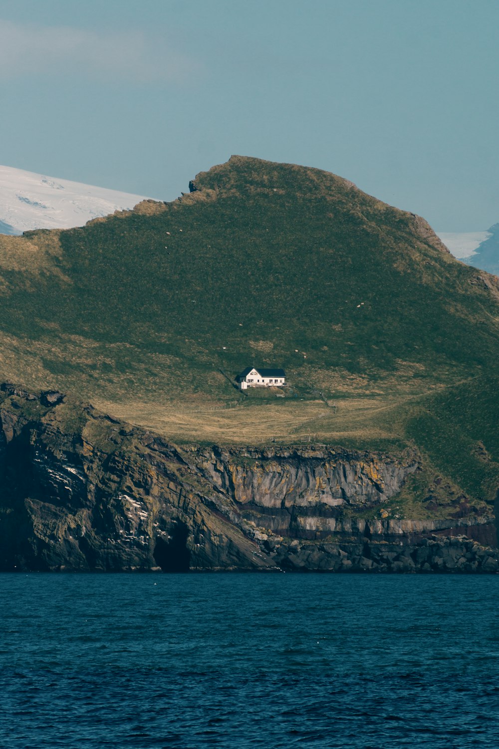 a house sitting on top of a hill next to a body of water