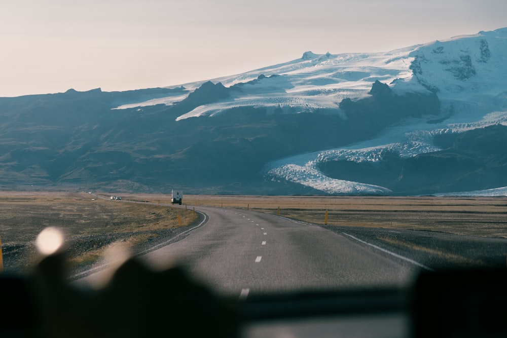 a car driving down a road with a mountain in the background