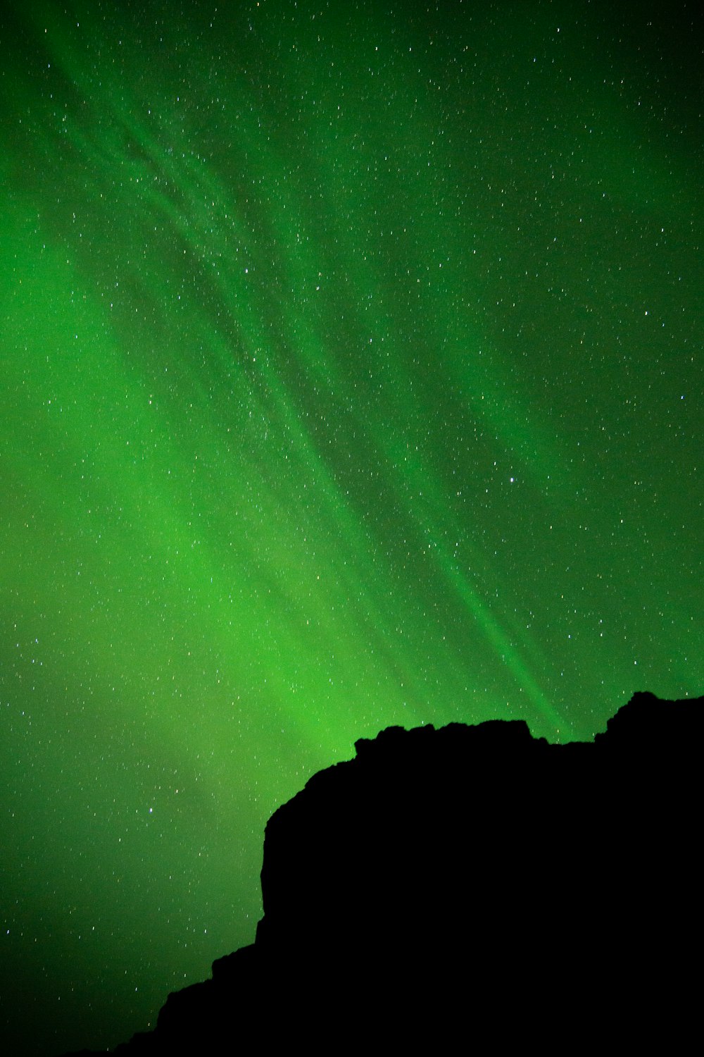 a person standing on top of a mountain under a green sky