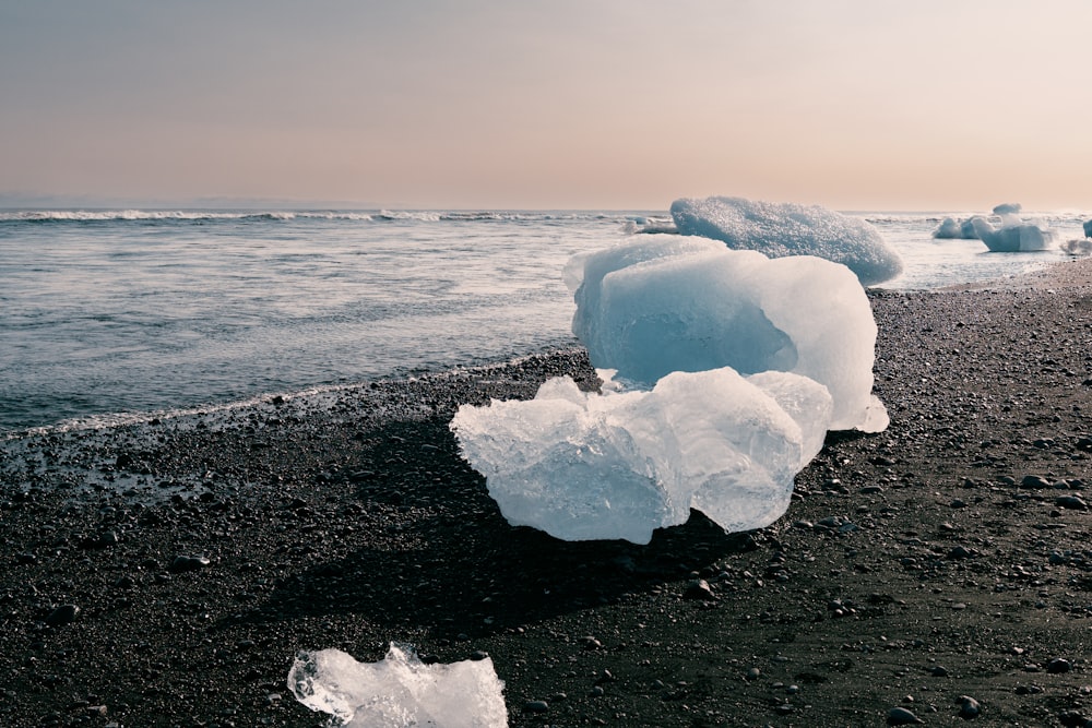 an iceberg on a beach with the ocean in the background