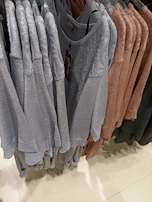 Soft knitted sweaters in gentle hues hanging on a minimalistic rack.