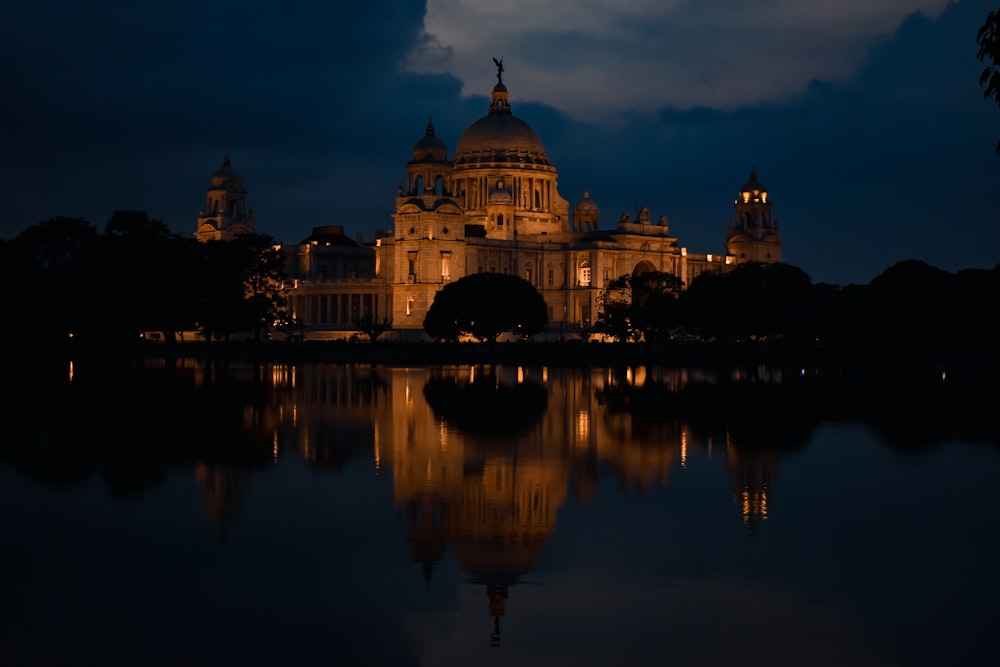 a large building sitting on top of a lake at night