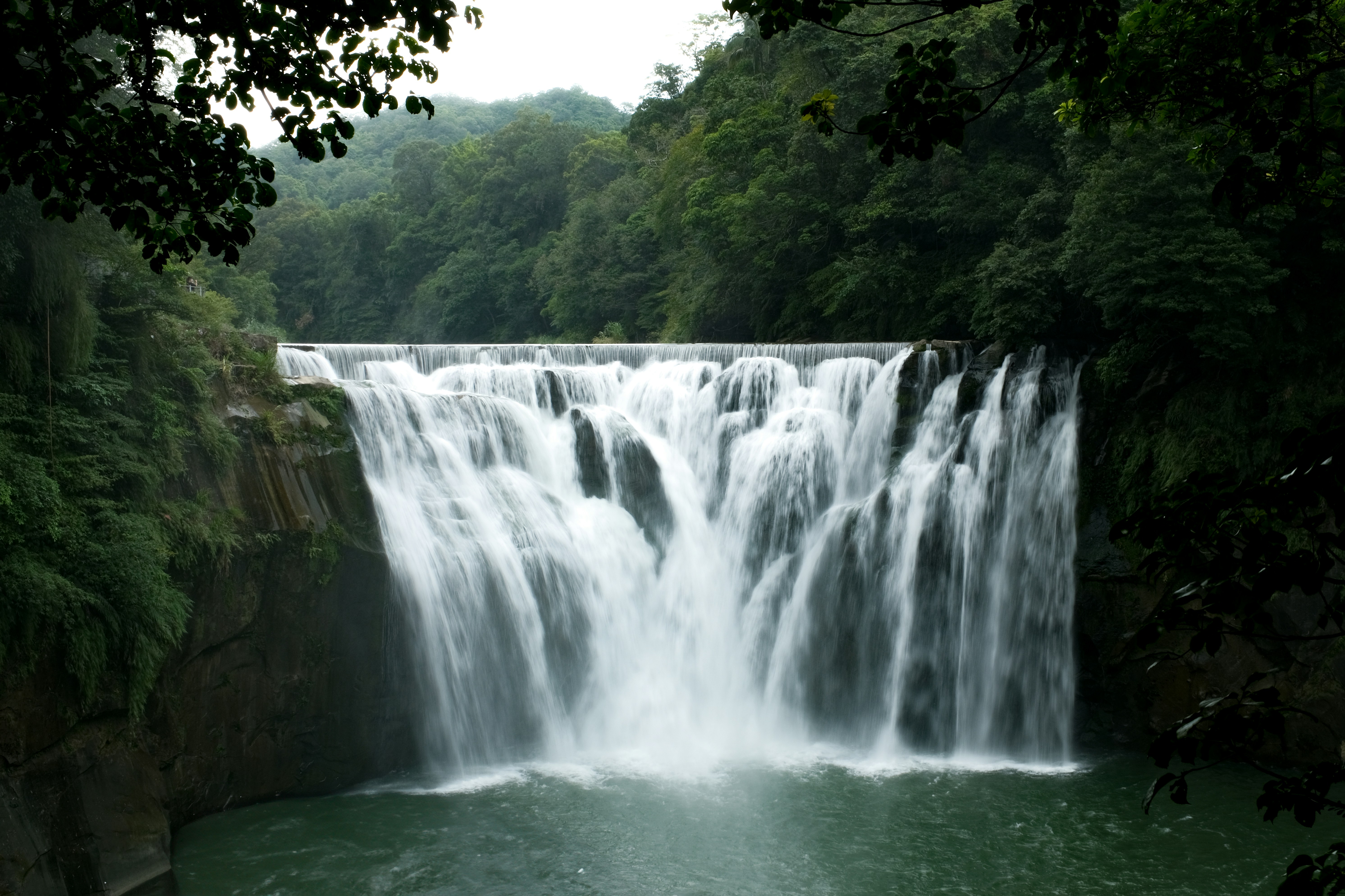 a large waterfall in the middle of a forest