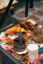 A vibrant artist's workspace with colorful paints and brushes scattered around a canvas.