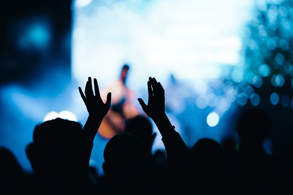 a crowd of people raising their hands in front of a stage