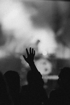Close-up of a winner's hand raised high, with a roaring crowd blurred in the background.