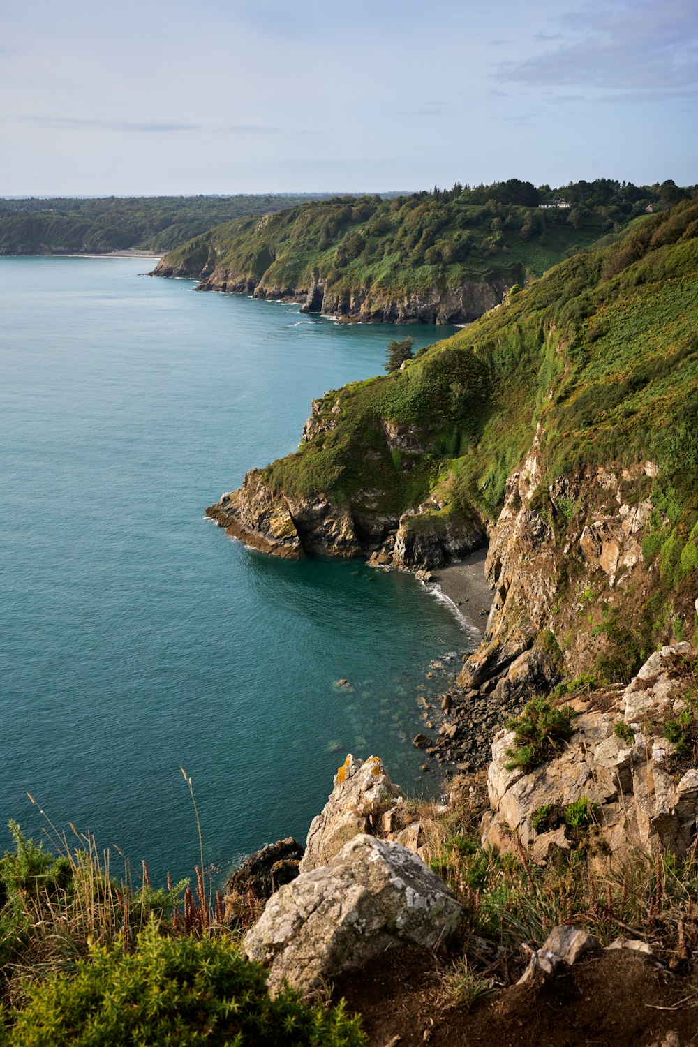 a large body of water surrounded by a lush green hillside