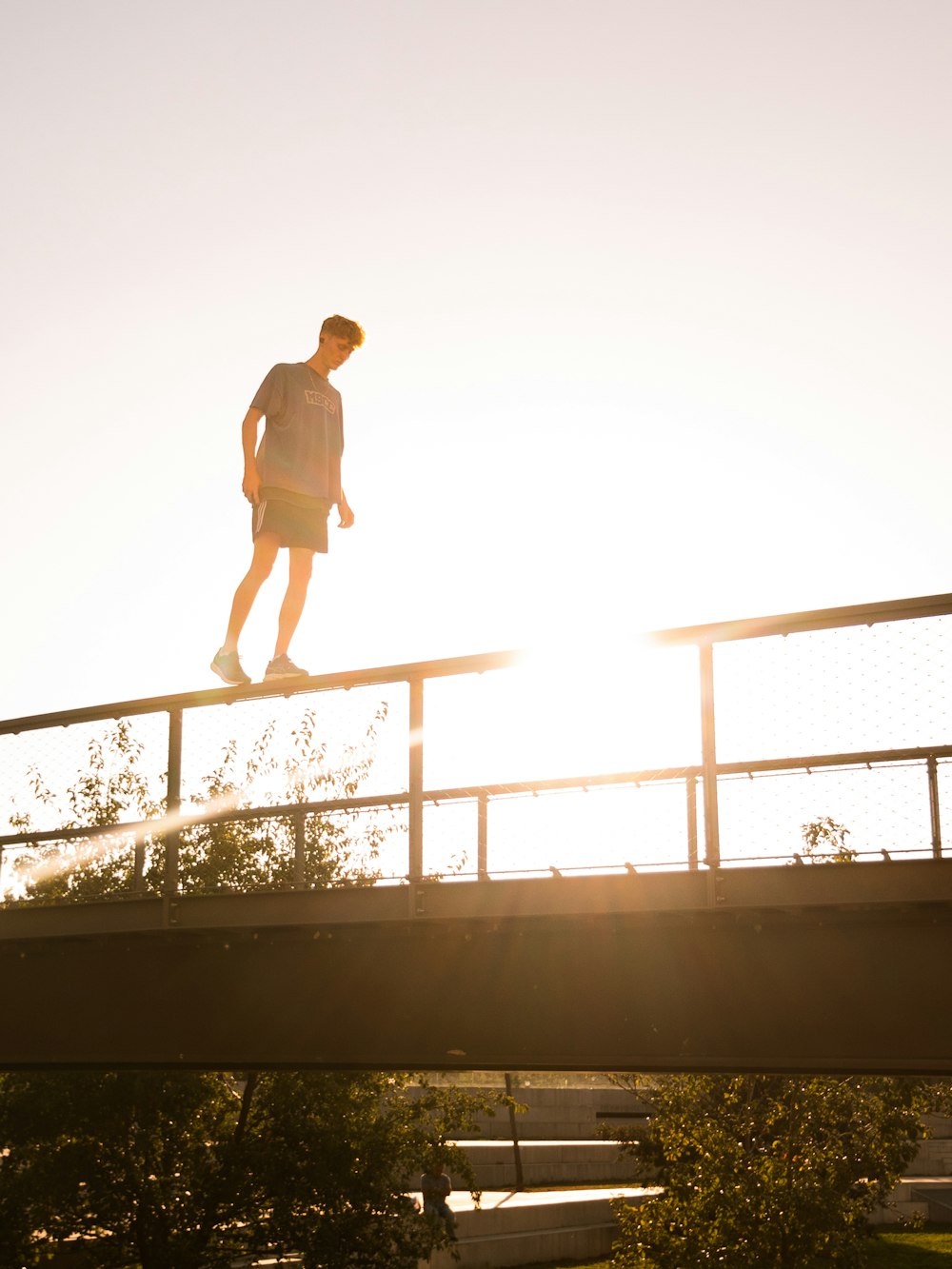 a man walking across a bridge over a river