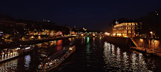 Nighttime shot of the Seine River reflecting city lights and passing boats